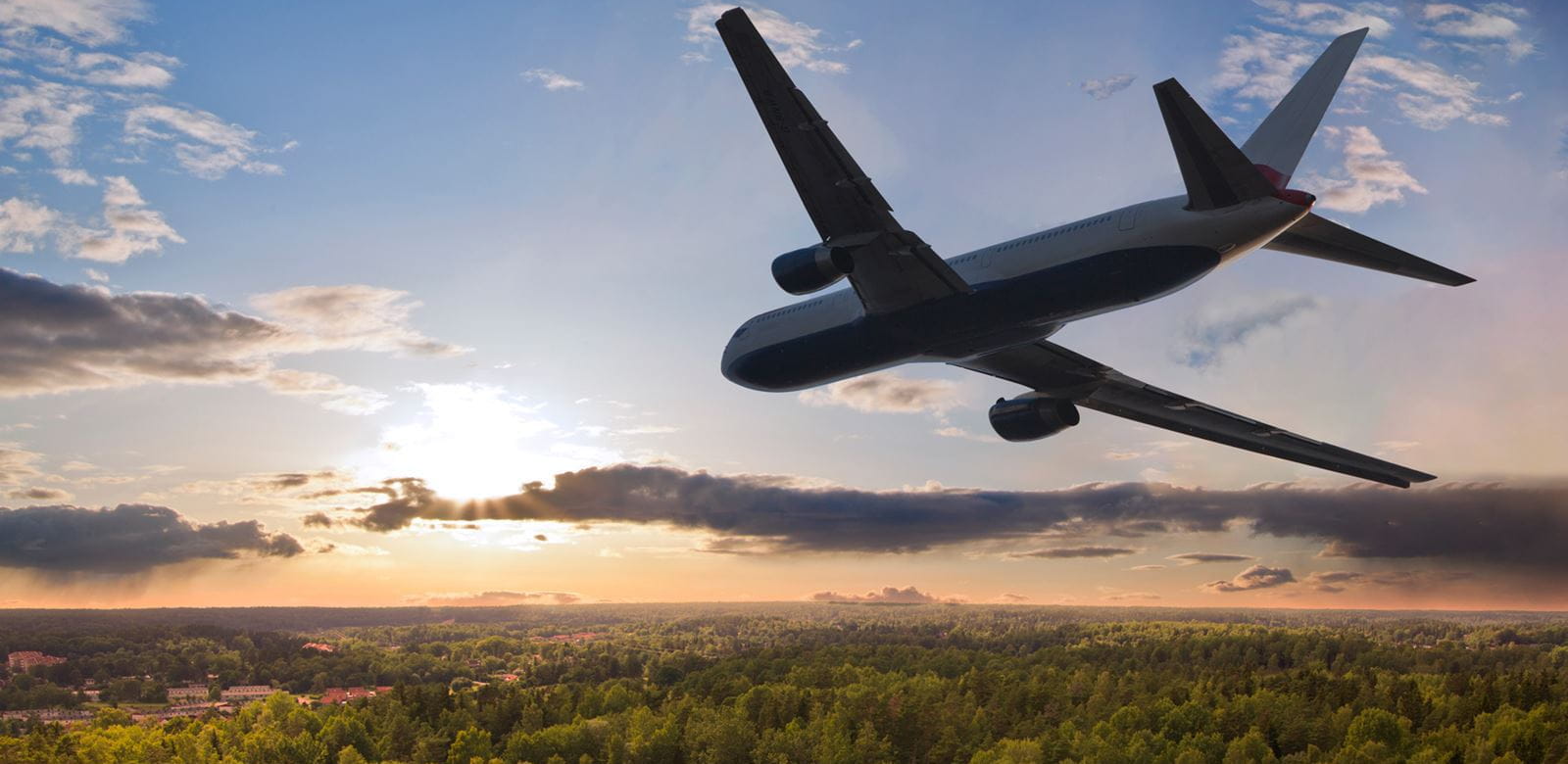 an airplane flying towards the sunset