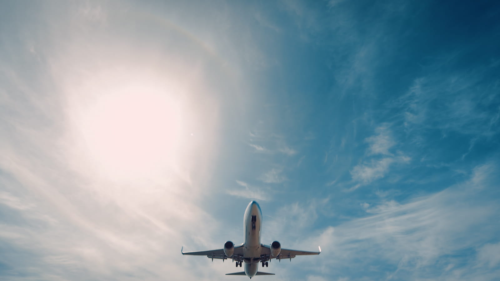 An airplane flying across cloudy blue sky