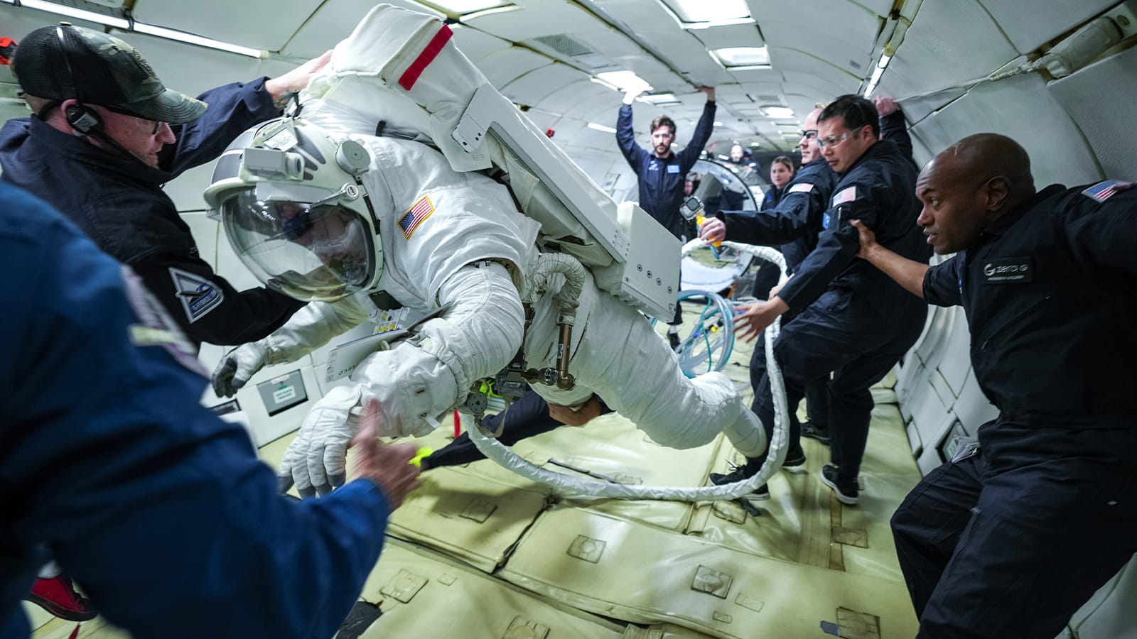 person in astronaut flight suit floating in the air inside a zero gravity airplane