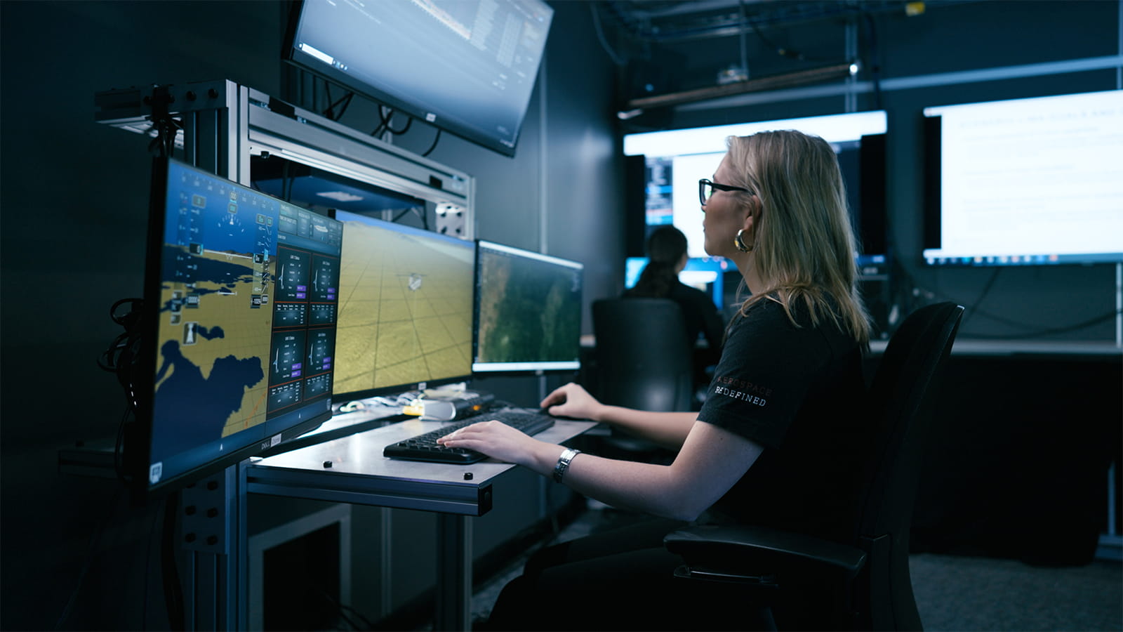 A woman working in-front of four computer monitors