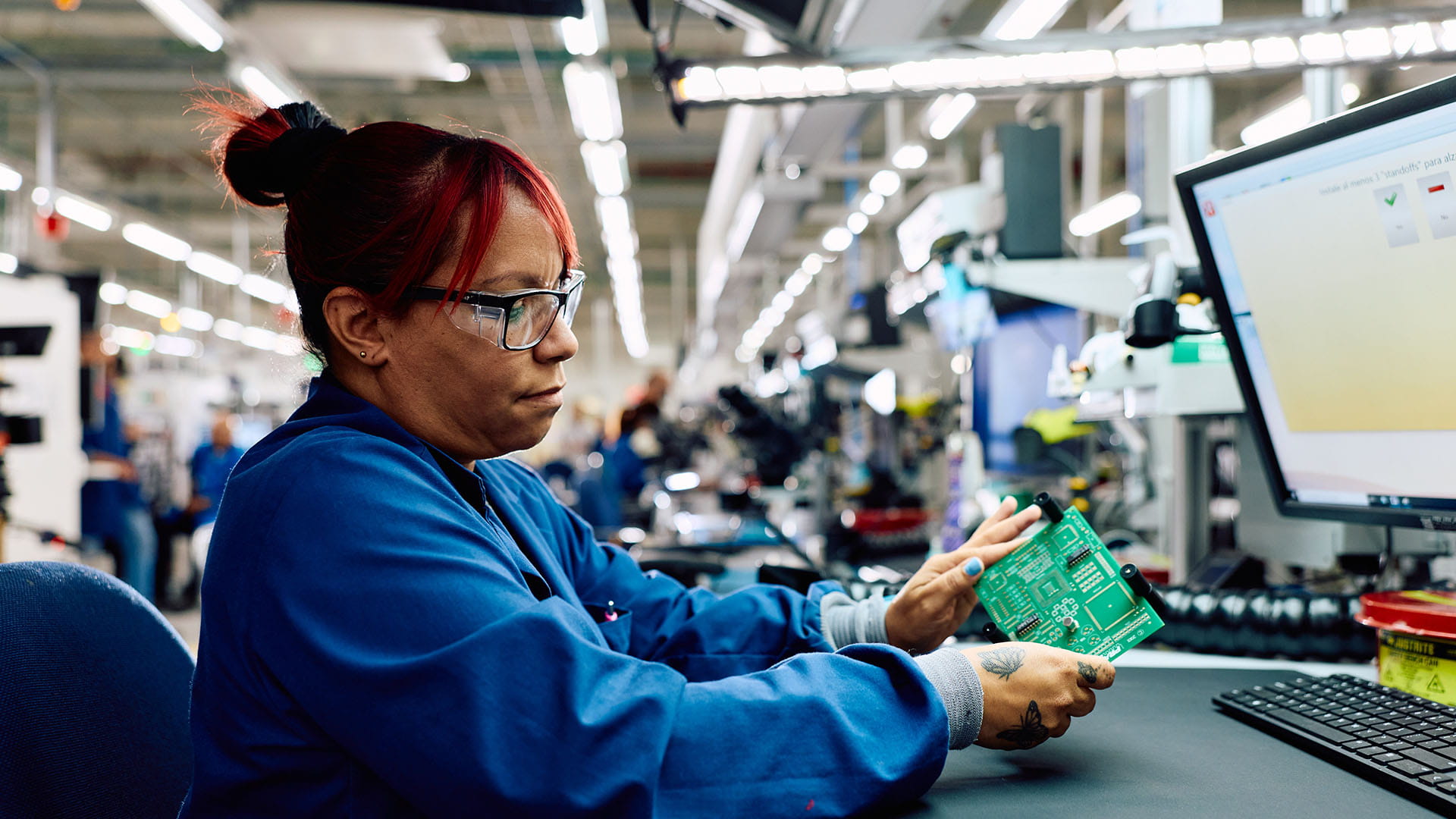 an operator assembles a cicuit board while observing a screen
