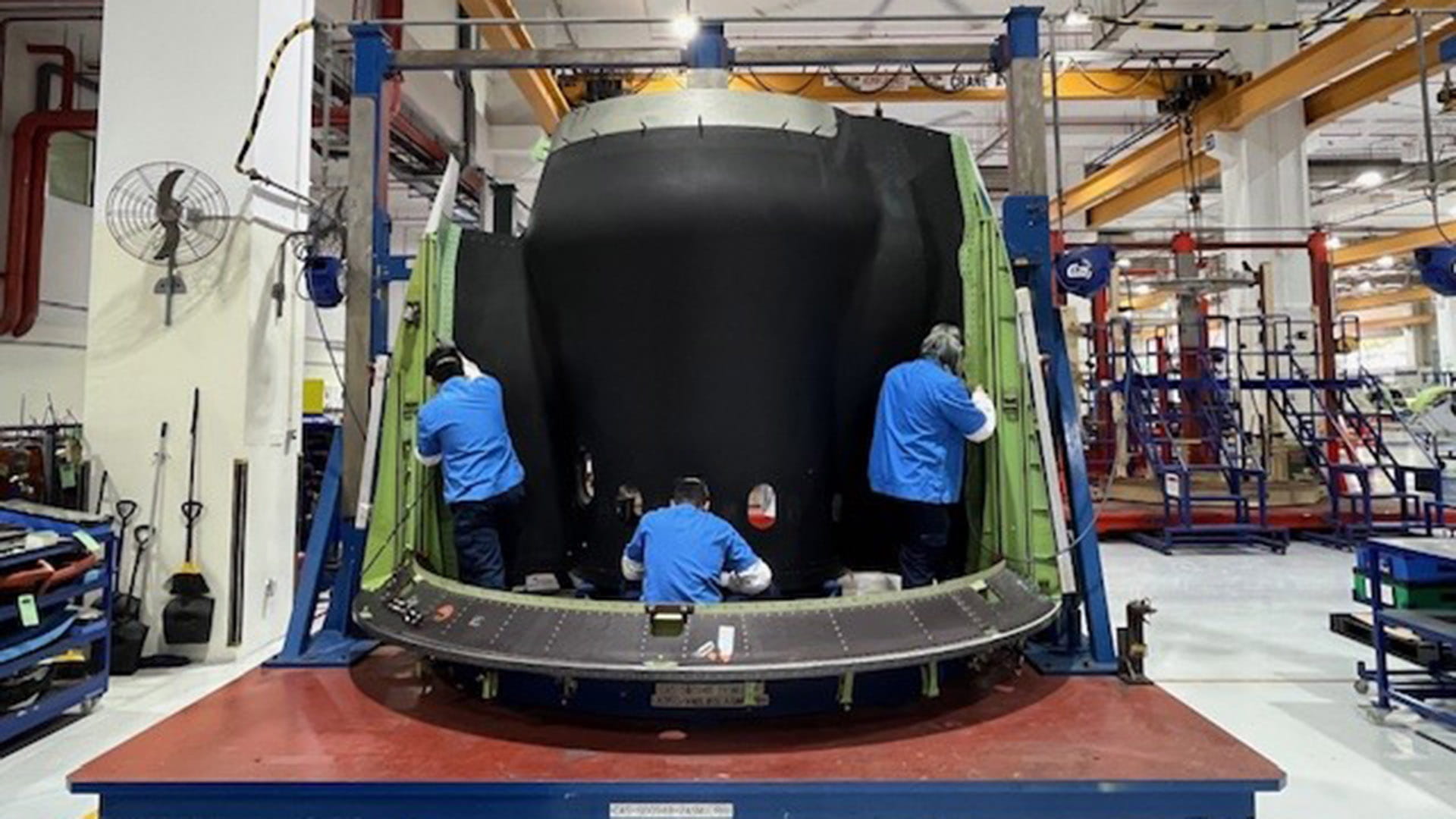 Three technicans work on part of a nacelle