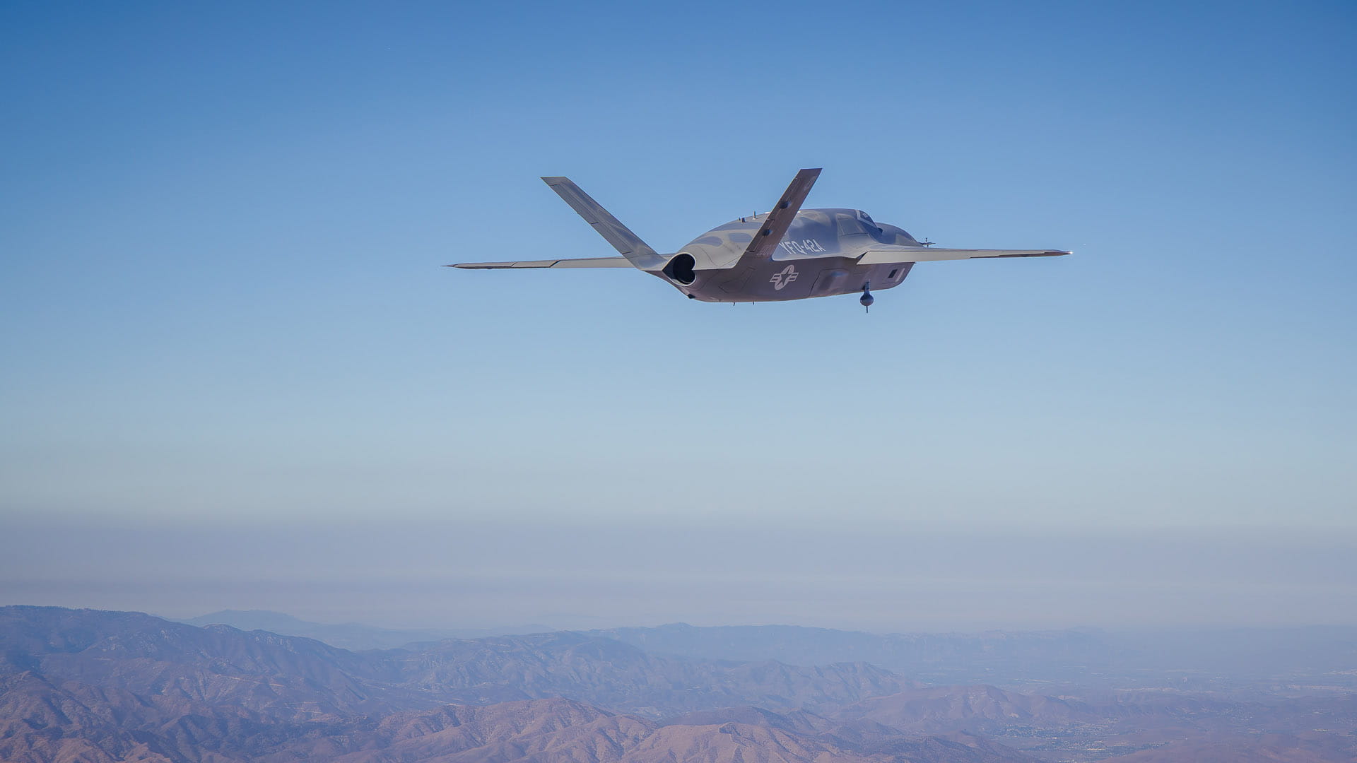 A fighter jet flying over a mountain range