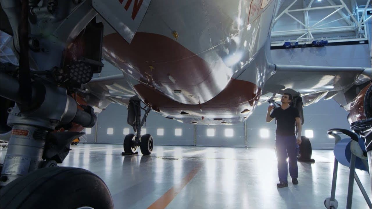 A technicain inspects an aircraft in a hangar