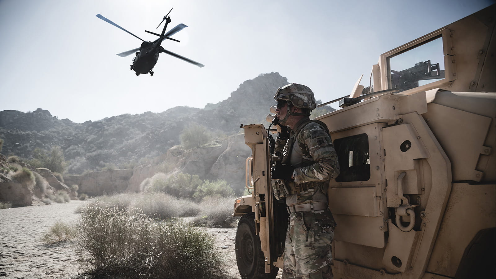 A helicopter flying above a U.S. army soldier