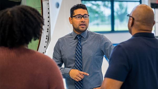 a man speaking to two employees about career opportunities