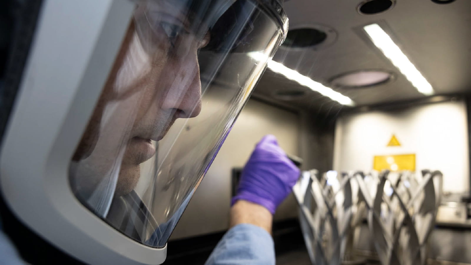 Man using 3D printer while wearing protective face shield