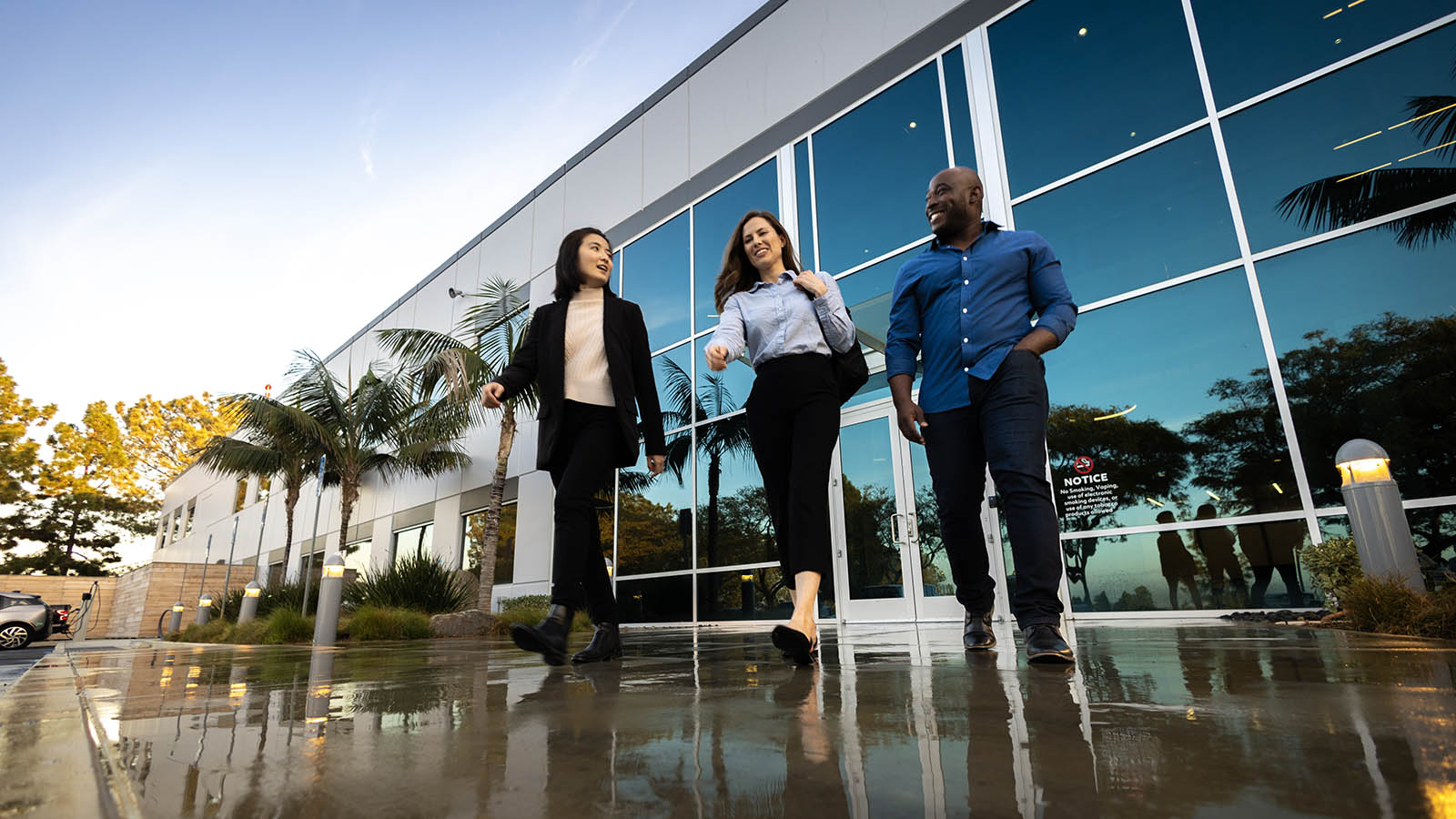 Three employees walking out of an office building