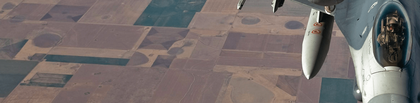 a jet in flight with munitions showing on wing