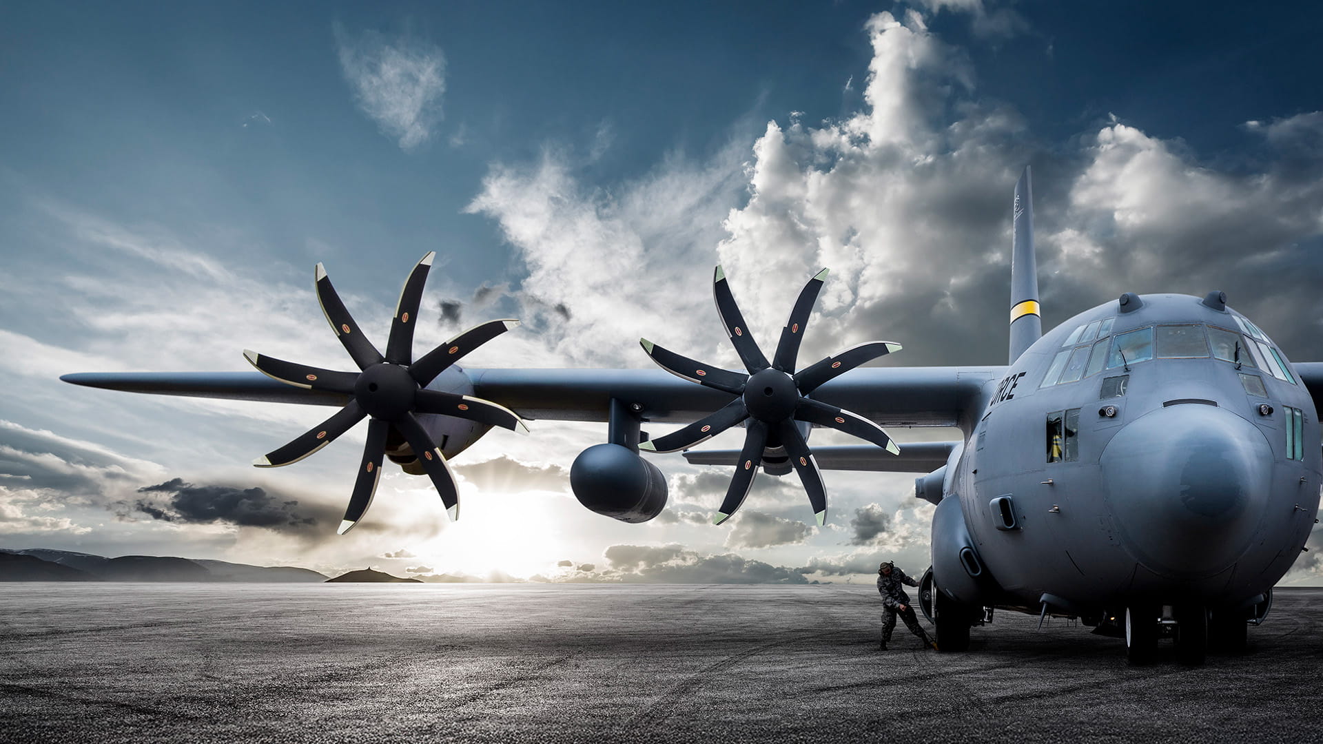 A ground crew member pulls chocks out from under the wheel of a C-130.