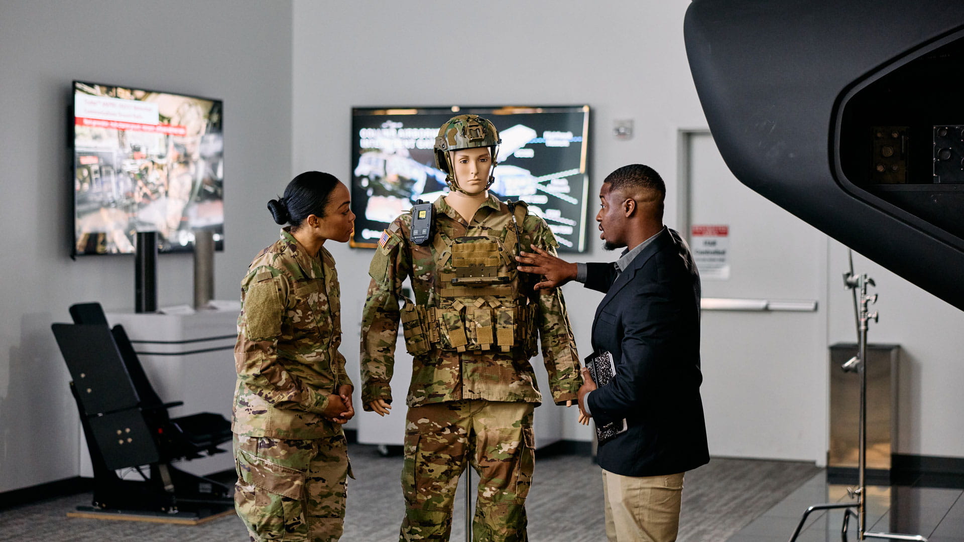 A suited man and a a woman in military camouflage view a mannequin dressed in camouflage