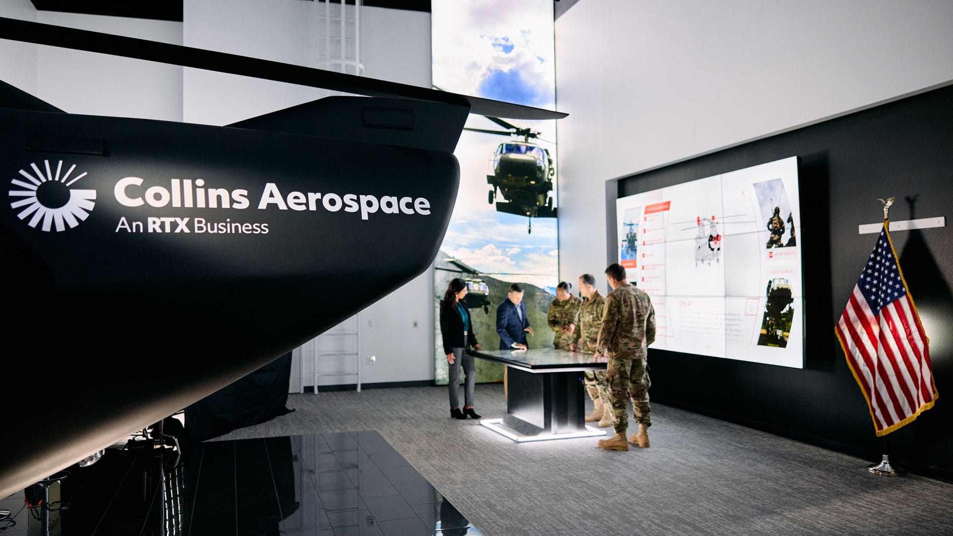 Three soldiers in fatigues and two people in suits working on an interactive table