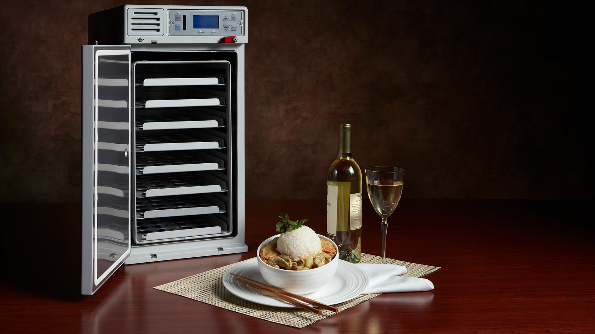 Endura Steam Oven pictured with a bowl of Chinese food, a bottle of wine, and a wine glass