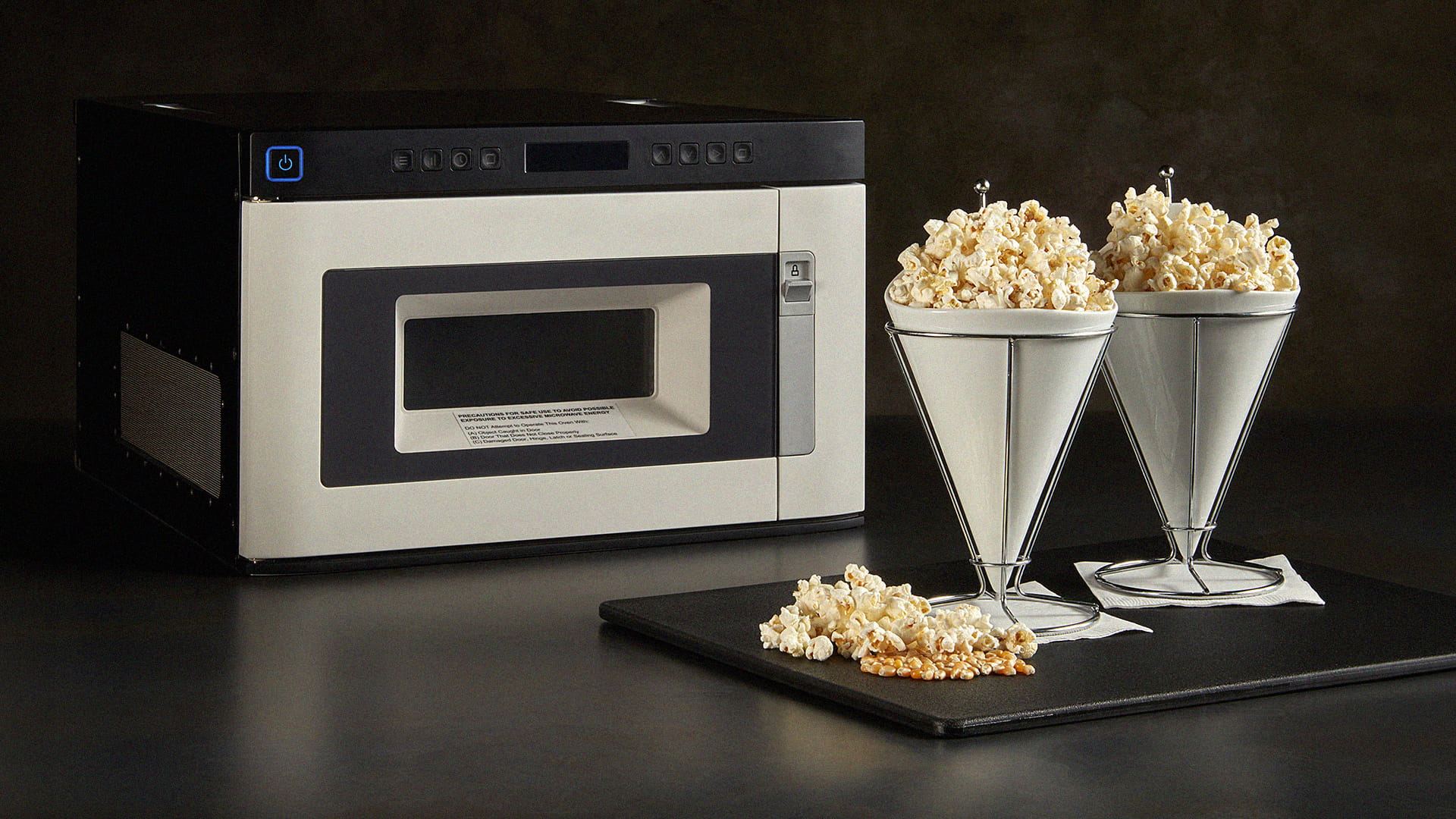 A small microwave with two cone-shaped bowls filled with popcorn