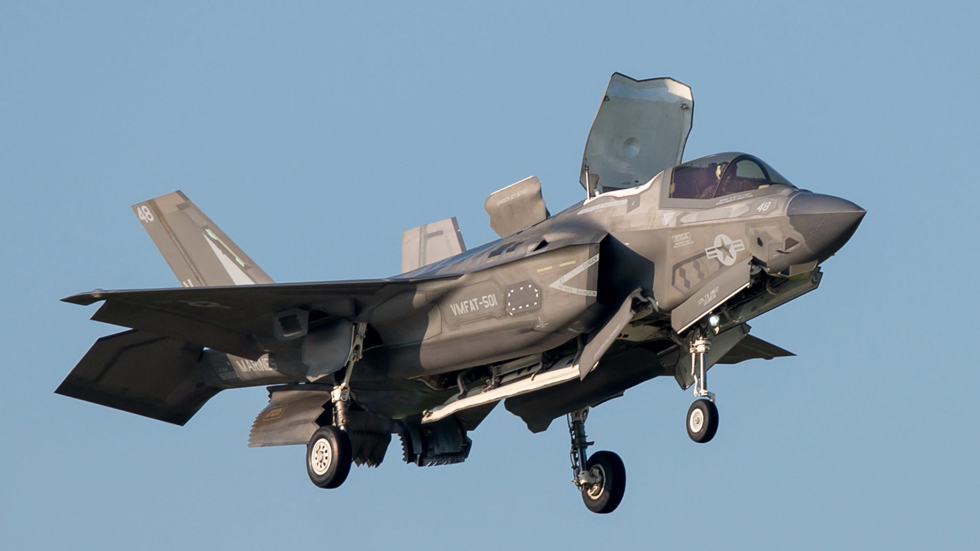 An F-35 in the air. Its wheels are down and the canopy is up.