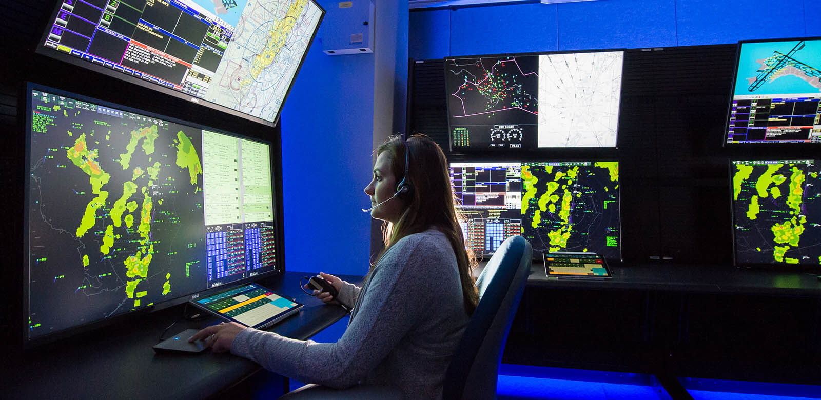 A woman views weather data and air traffic while working in an air traffic control position