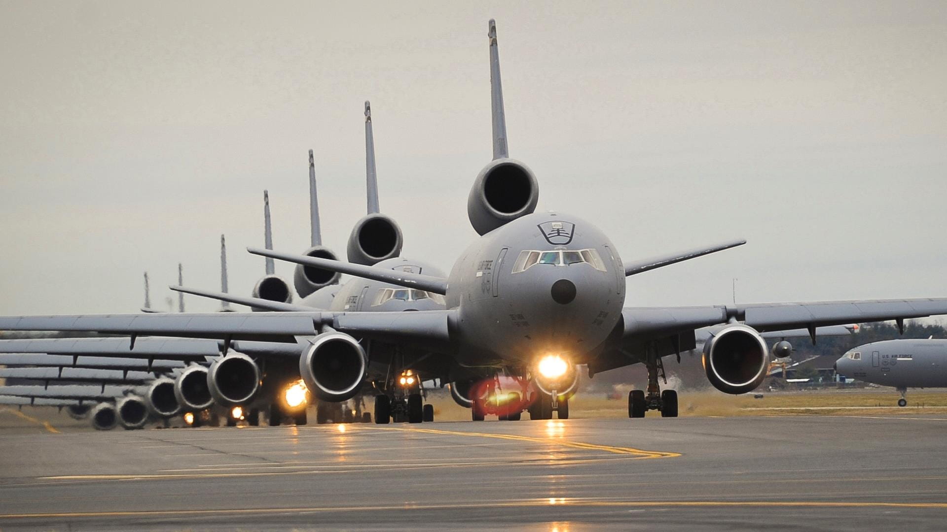 Black and white, line of KC390s getting ready to take off on runway