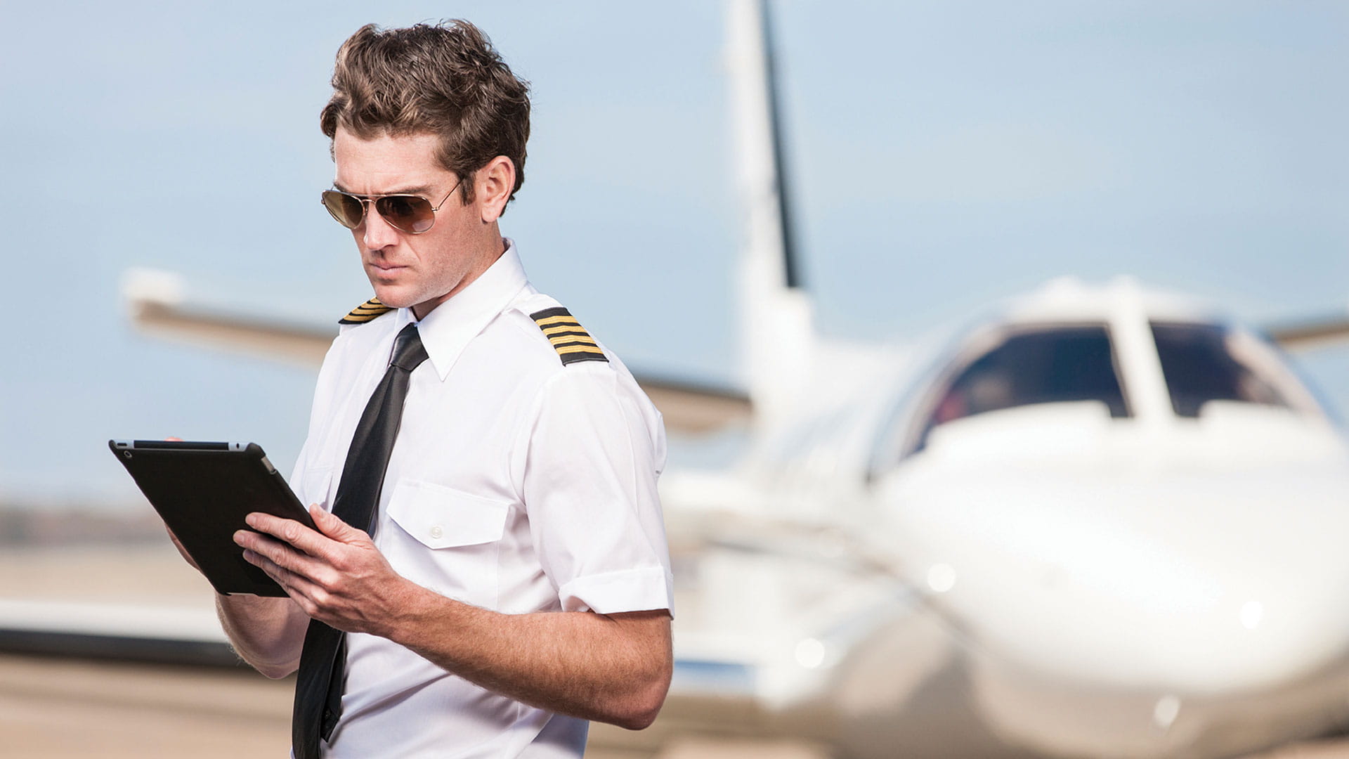 Pilot in front of jet using tablet