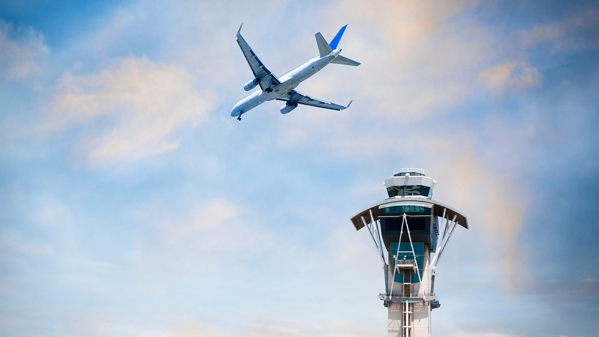 An aircraft flies over an air traffic control tower