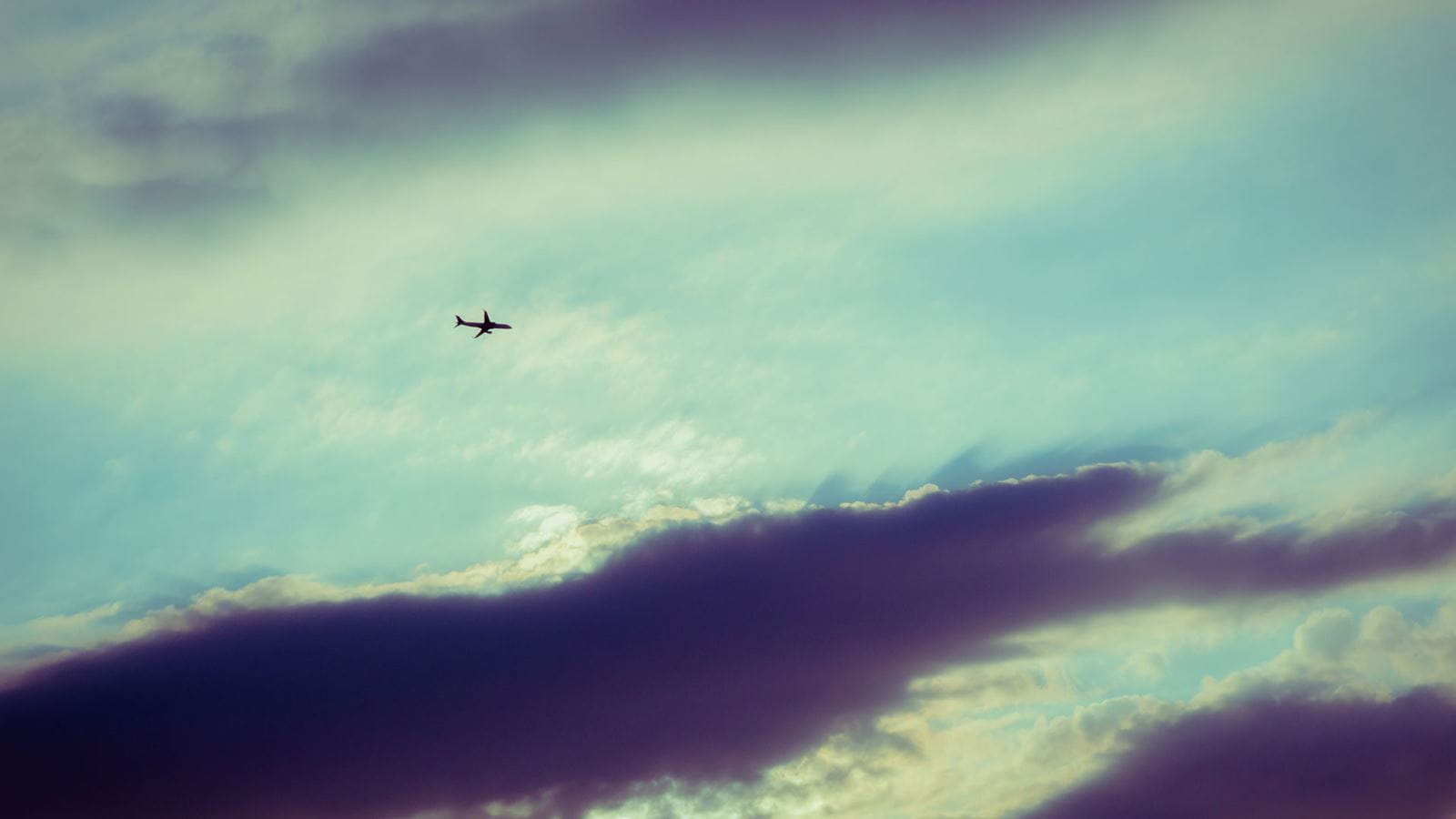 Silhouette of an airplane flying in sunset sky