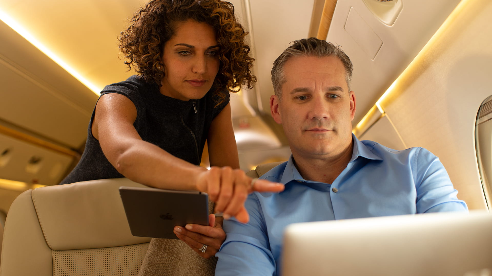 People conversing over viewing tablet in jet