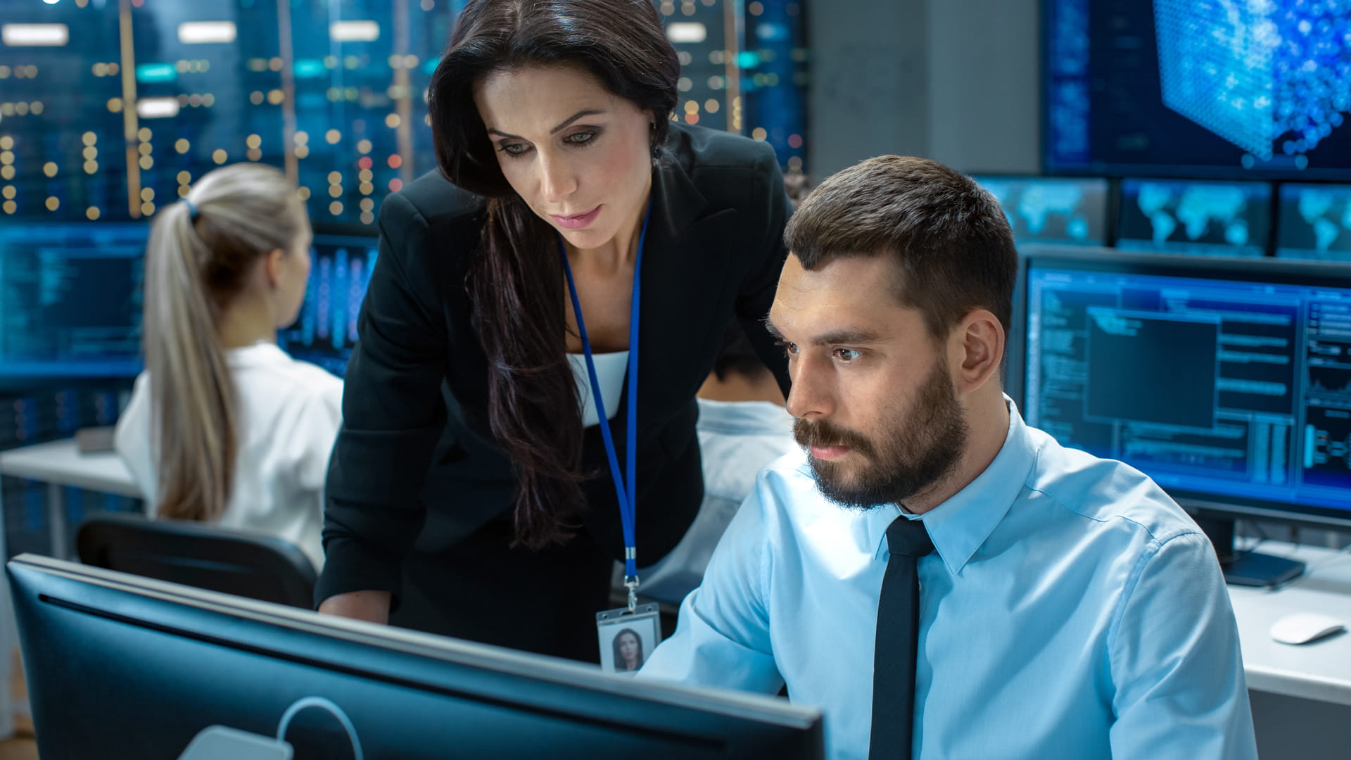 a man and a woman in office attire looking at a computer screen