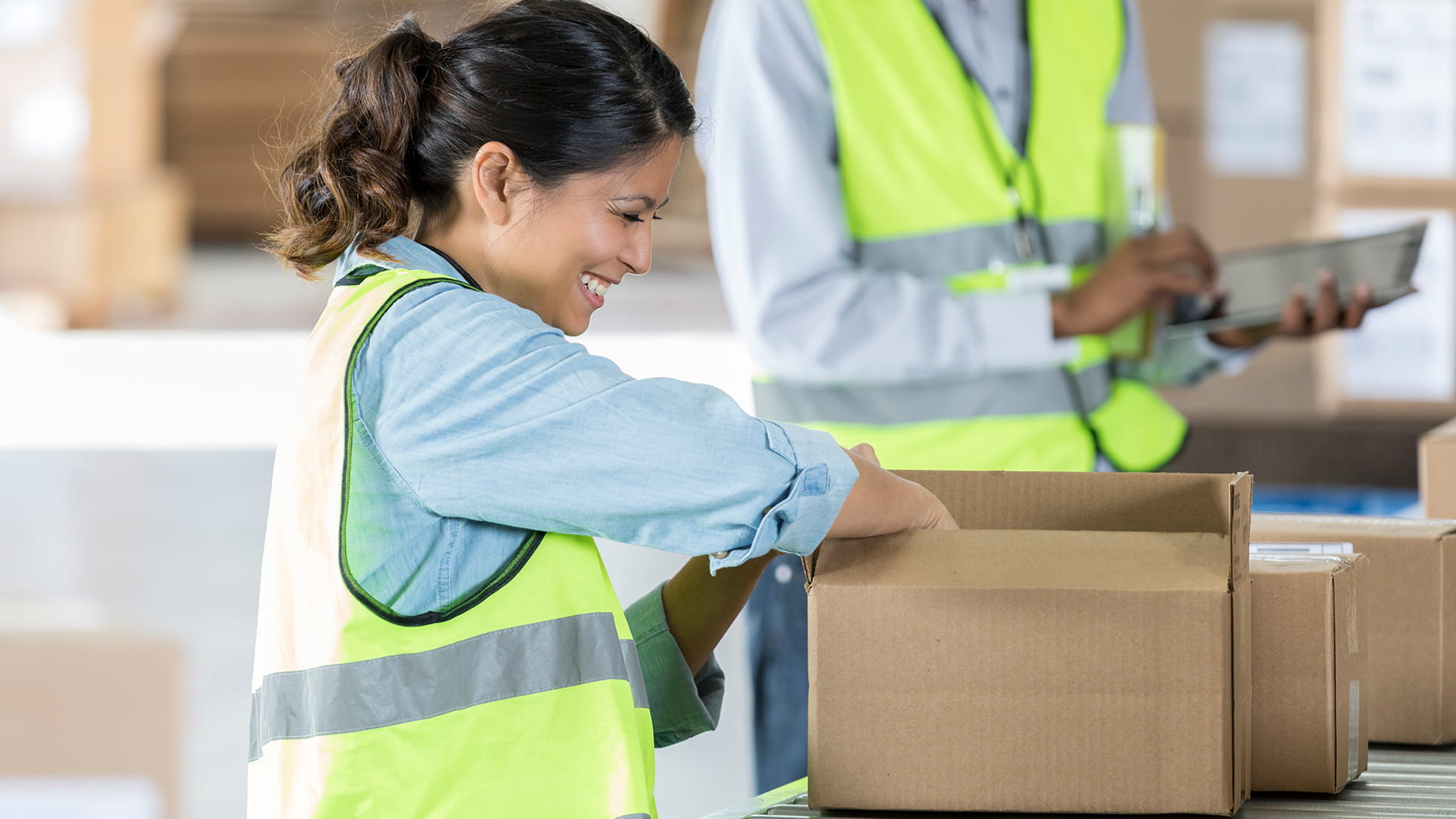 Woman wearing reflective vest reaching into box