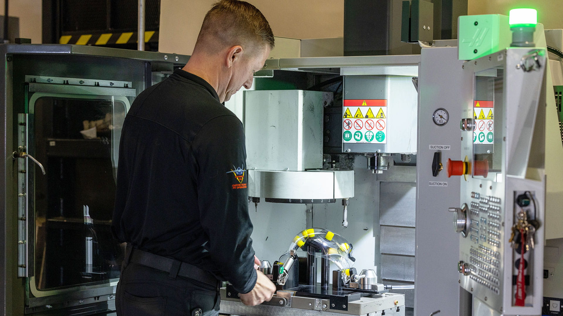 Technician in the Pilot Readiness Facility (PRF™) using a fabrication machine on helmet visor trim