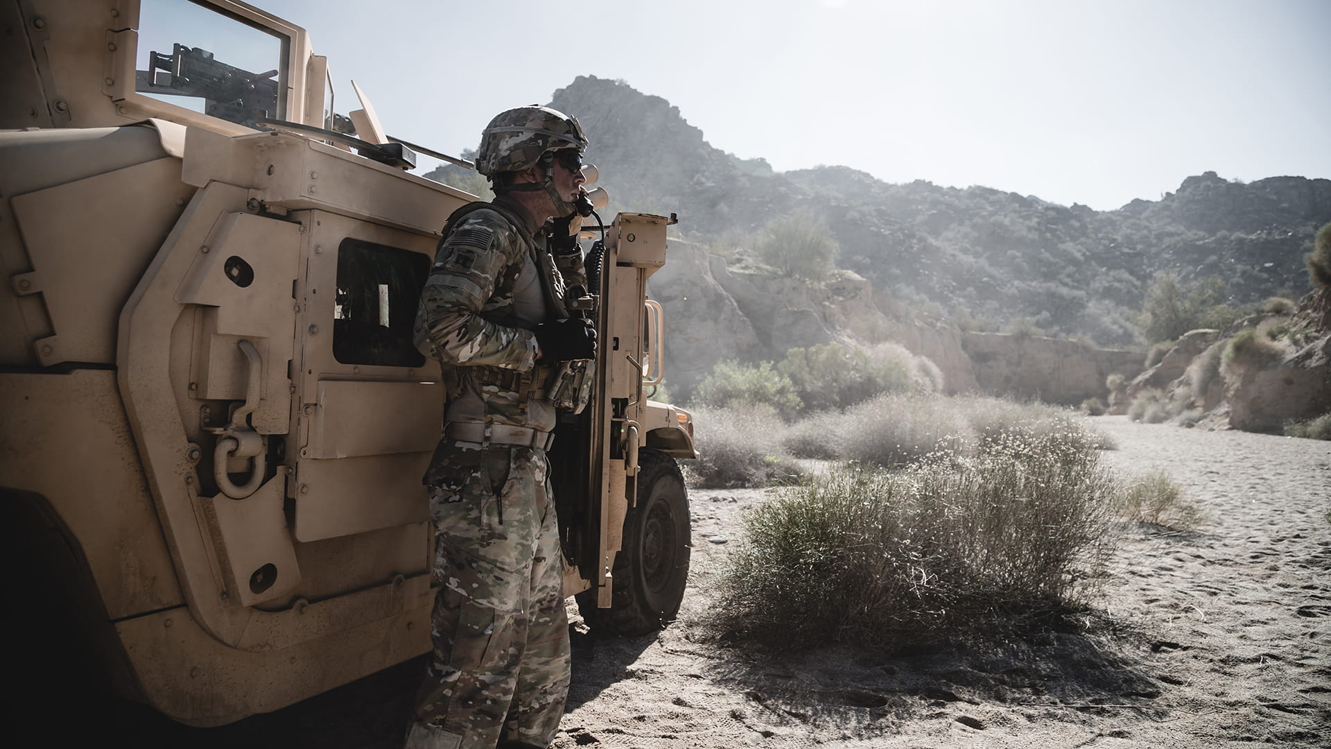 a desert soldier standing next to a humvee