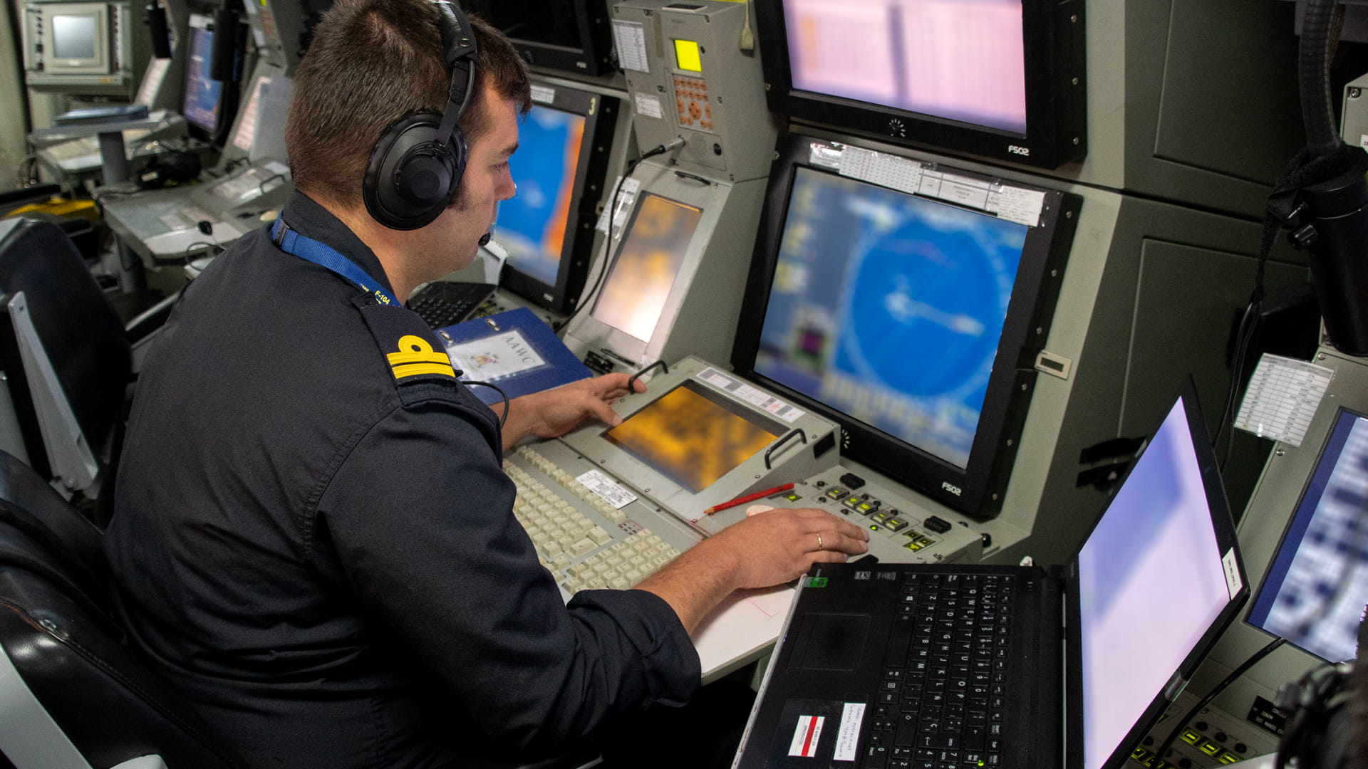 A man wearing headphones sits at a computer terminal