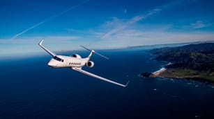 a private jet flying above the ocean