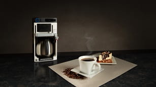 steaming cup of coffee and coffee maker