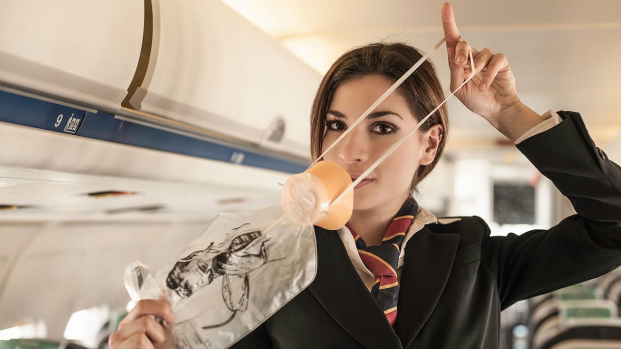 flight attendant demonstrating how to use oxygen mask