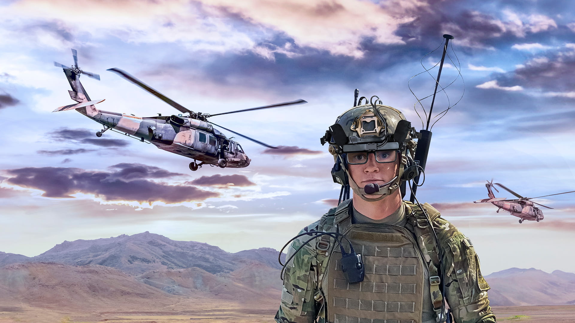 A soldier wearing a helmet-mounted display stands in the foreground. Two helicopters are visible in the background.