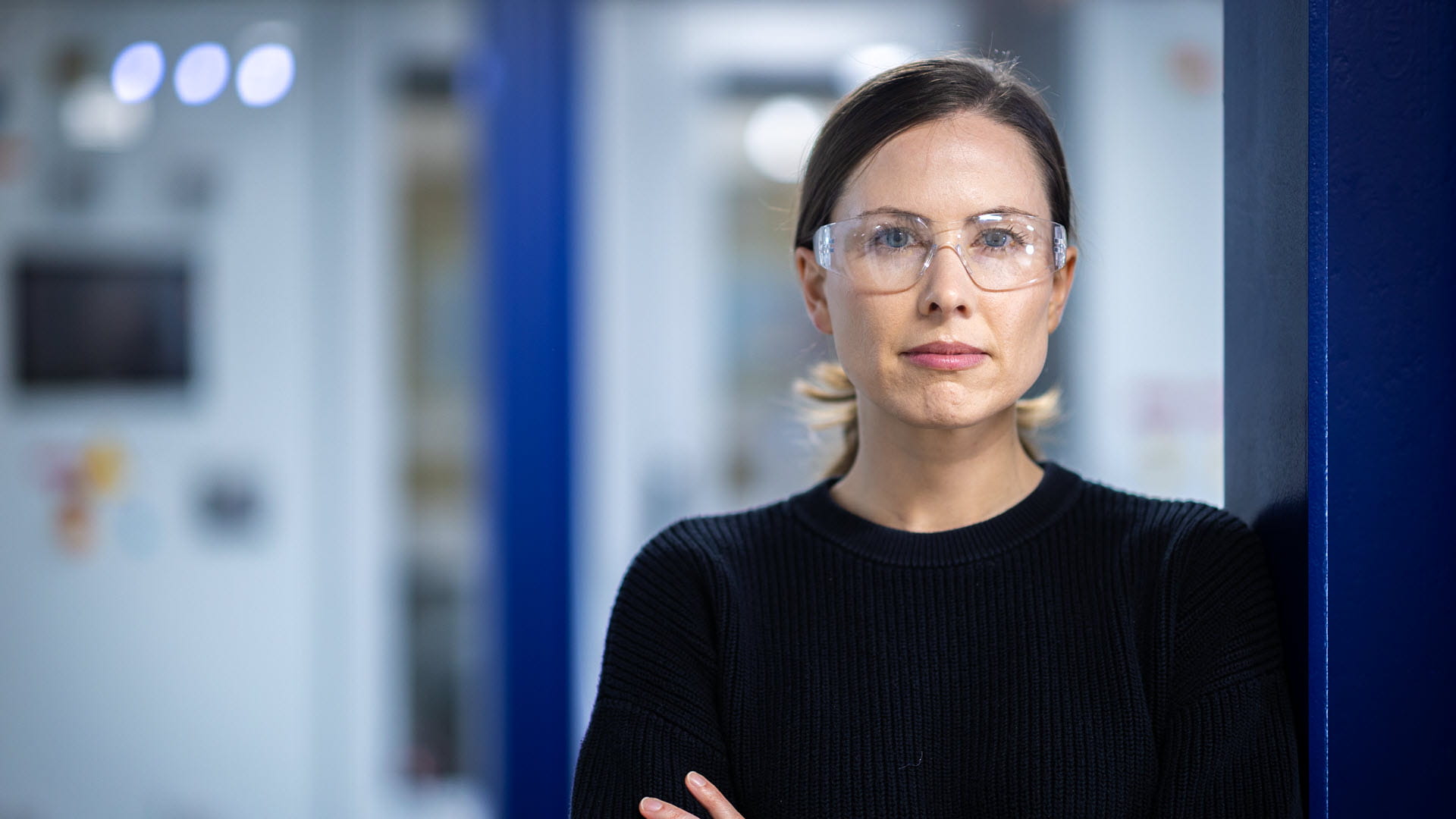 A woman in glasses standing in a doorway with her arms crossed