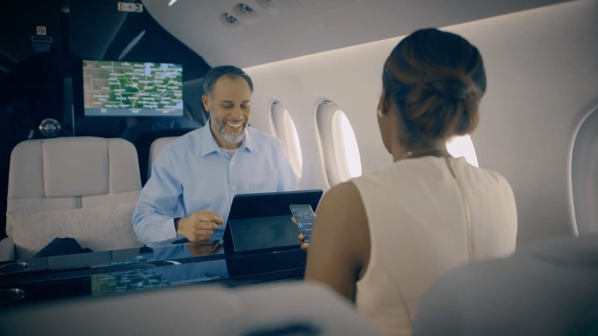 A man and woman in a business jet cabin enjoy entertainment offerings enabled by Collins Aerospace's Venue CMS