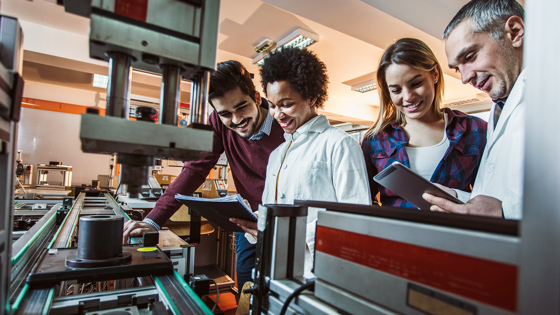 Team of scientists working together in a factory while examining scientific data of a production machine.
