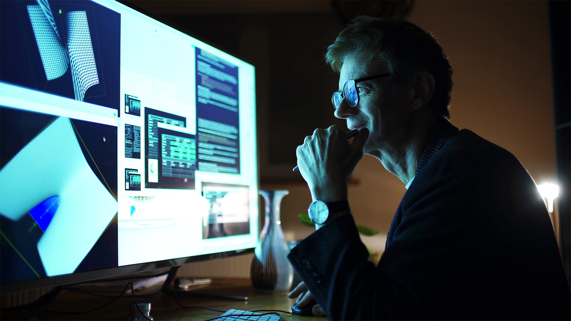 Close up stock photograph of a man working with a large computer screen. He’s working with 3D software examining complicated shapes.