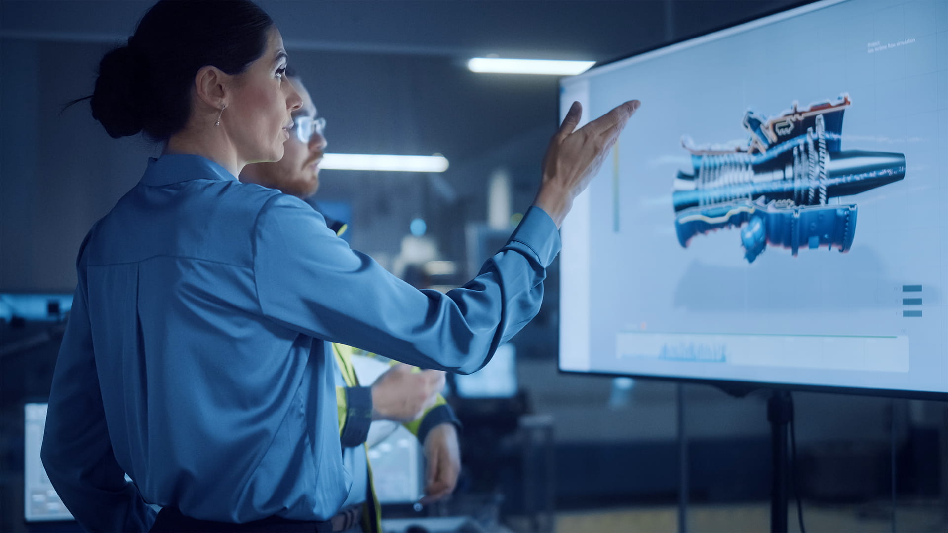 Female manager talks to male engineer, watching interactive digital whiteboard TV that shows new sustainable eco-friendly engine 3D concept.