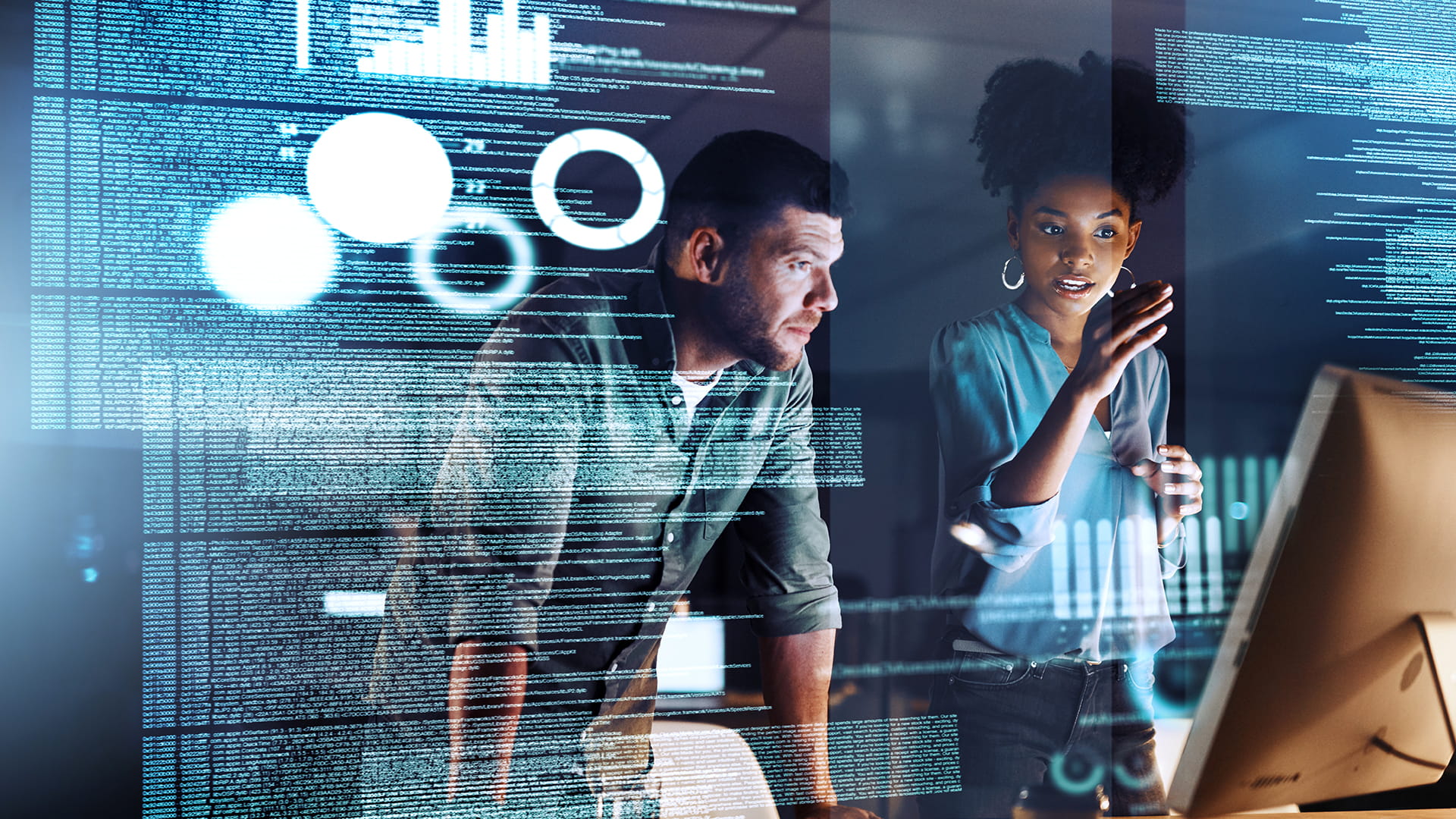 Two programmers working together on a computer code at night