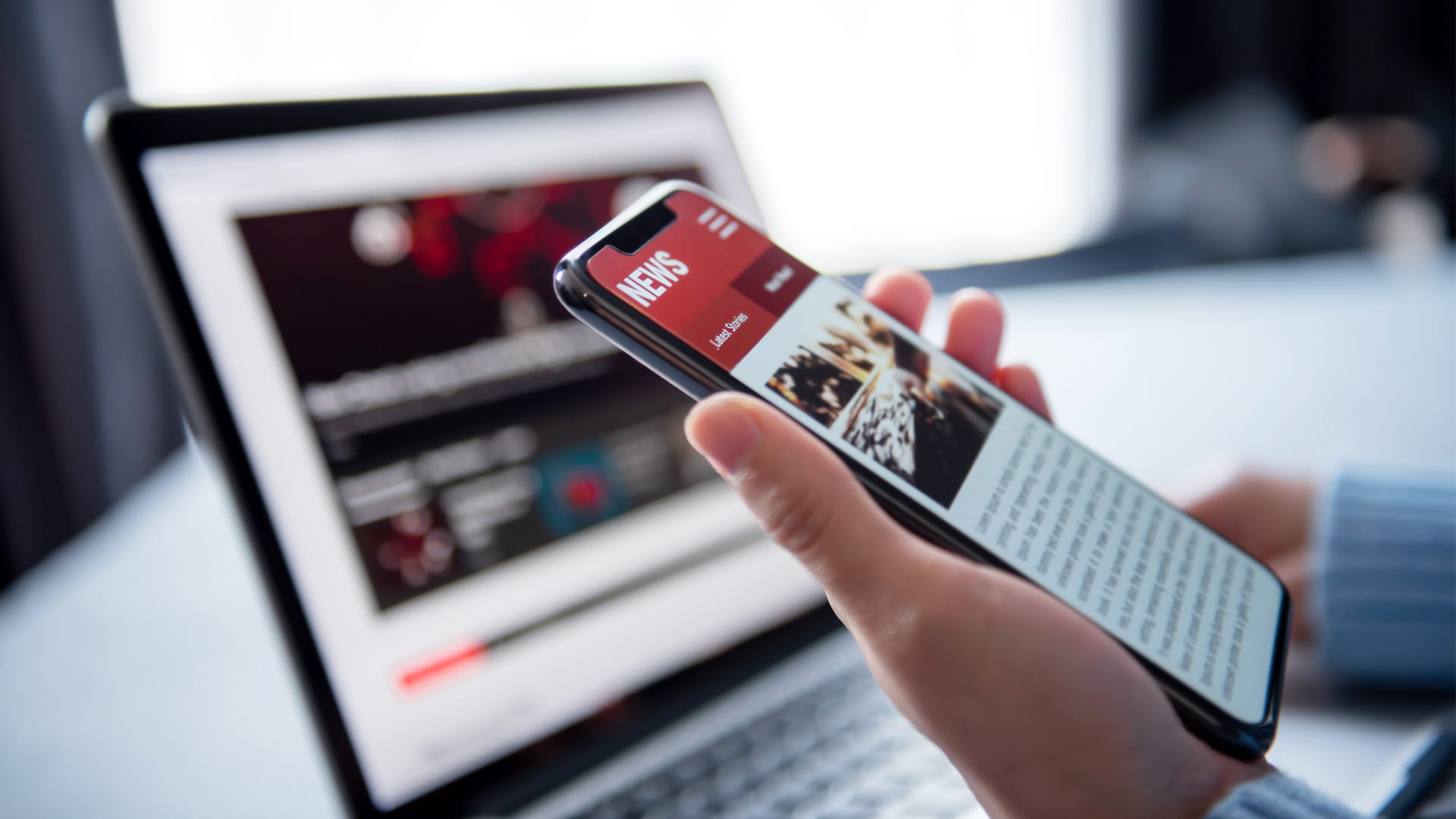 Woman reading news or articles in a mobile phone screen application at home.
