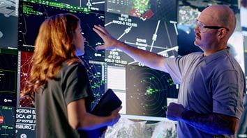 Controllers interact with advanced airspace surveillance and automation displays at a Collins Aerospace facility