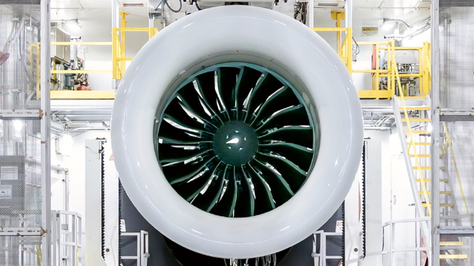A large turbofan engine viewed from the front in a test cell