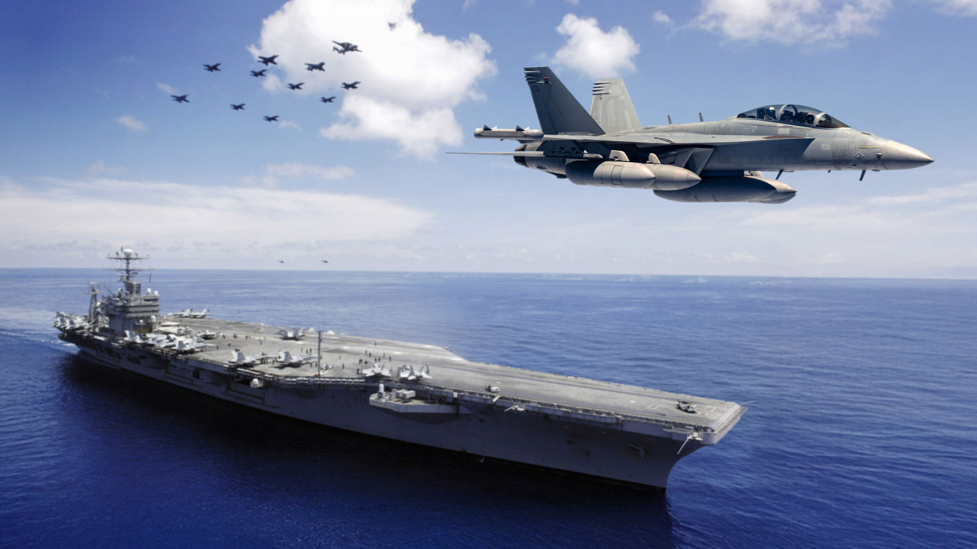 Fighter jets flying over an aircraft carrier