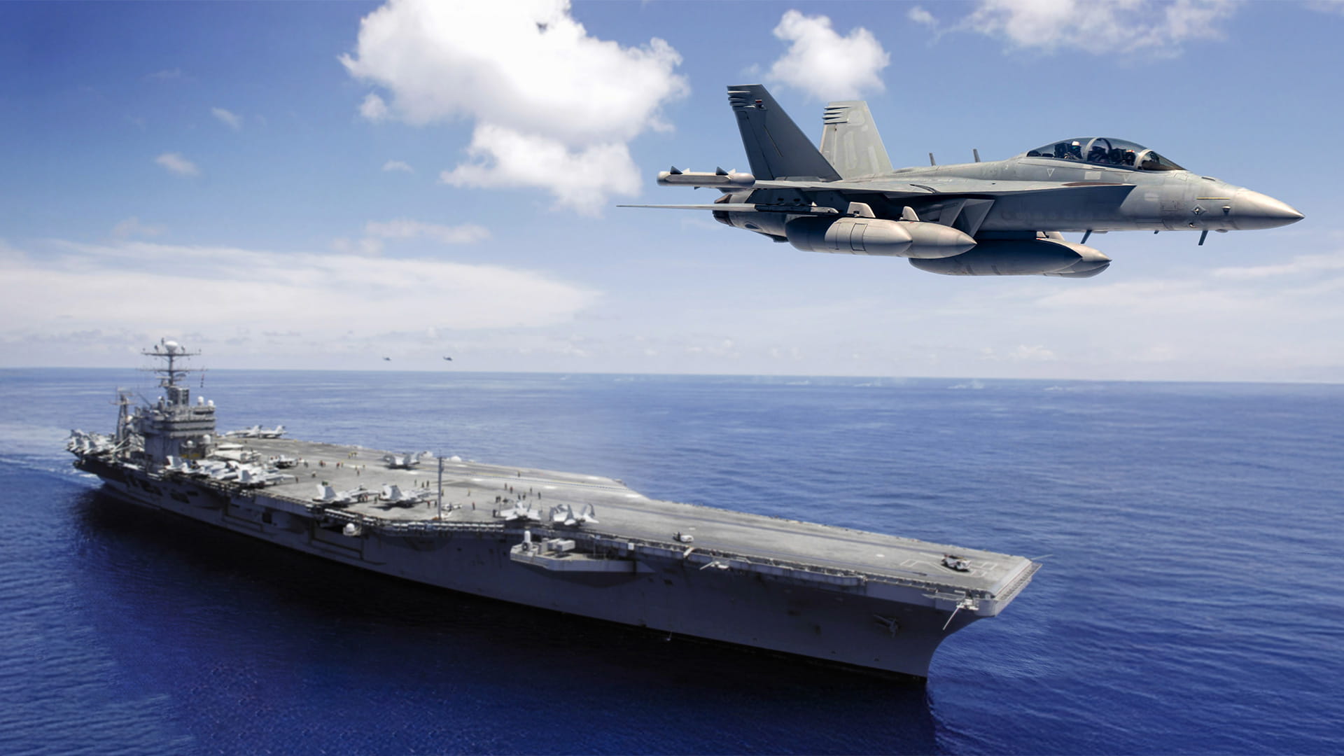 Fighter jets flying over an aircraft carrier