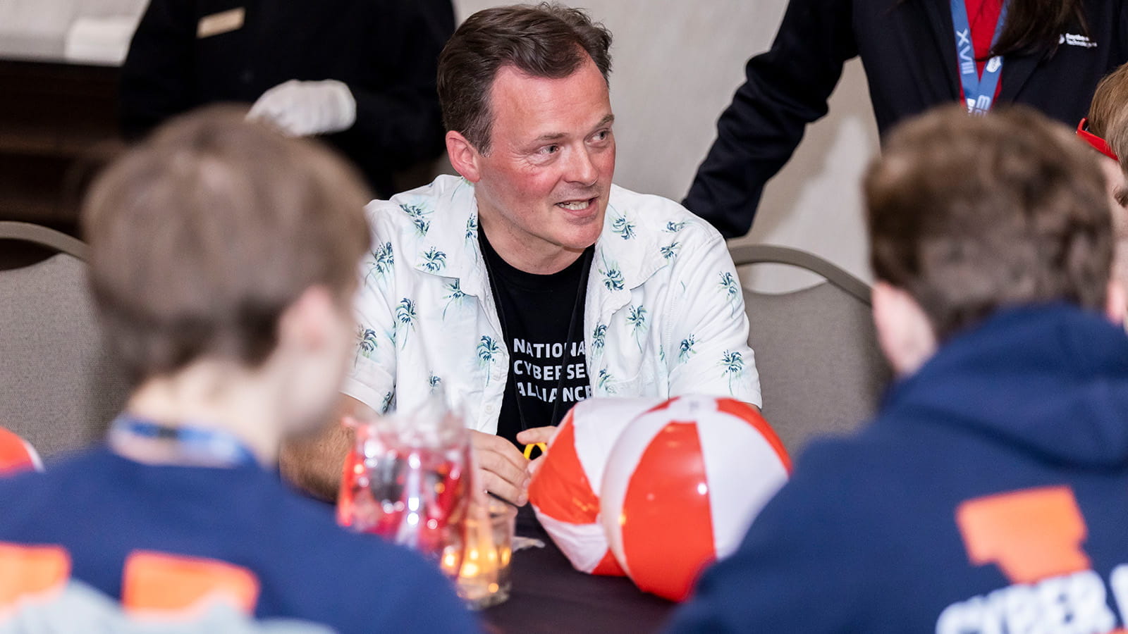 man with students at table talking