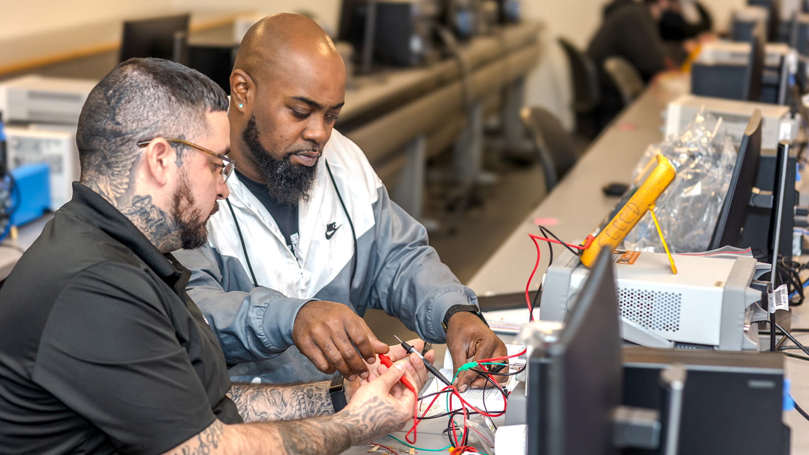 assembly technicians connect LEDs to a “bread board” with push switches and a variety of resistors