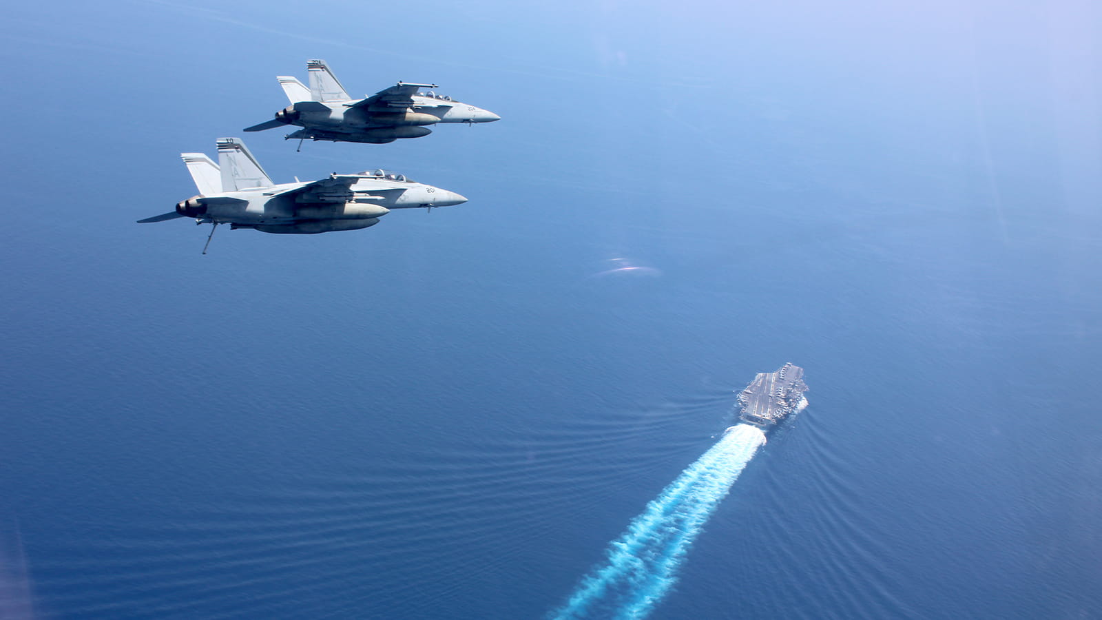 F/A-18F Super Hornets from the “Mighty Shrikes” of Strike Fighter Squadron (VFA) 94 fly in formation above the aircraft carrier USS Nimitz (CVN 68)