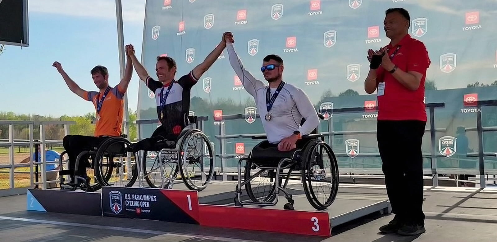 Three athletes pose on stage with their medals at the 2022 Paralymipcs
