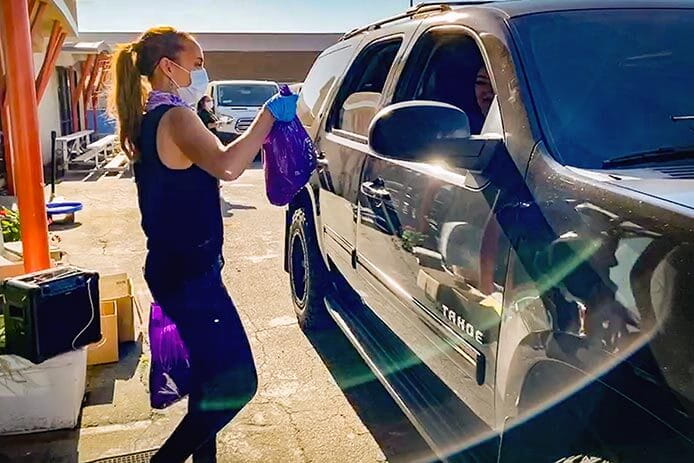 Jen Prindle, a Raytheon Technologies employees, hands meals to a family at the Boys & Girls Clubs of Los Angeles Harbor.